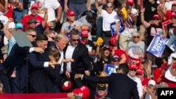 Obezbeđenje odvodi ranjenog Donalda Trampa sa bine, 14. jul 2024. (Rebecca DROKE / AFP)