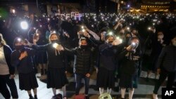 Para pengunjuk rasa melambaikan ponsel pintar mereka sambil menyanyikan "Glory to Hong Kong" dalam unjuk rasa untuk siswa sekolah menengah di dekat Museum Seni Hong Kong di Hong Kong, Jumat, 13 Desember 2019. (AP/Mark Schiefelbein)