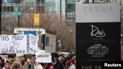 Des manifestants tiennent des pancartes de protestation devant l'hôtel Trump à Vancouver, Canada, le 28 février 2017.