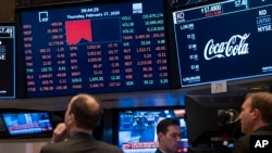 Stocks reflect declines on monitors as people work on the floor of the New York Stock Exchange, Feb. 27, 2020.