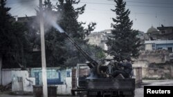 A Free Syrian Army fighter fires an anti-aircraft artillery weapon during an air strike in Binsh near Idlib, December 23, 2012. 