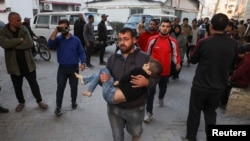 A man carries a Palestinian casualty to a hospital, in the aftermath of an Israeli strike, in Gaza City, Dec. 19, 2024. 