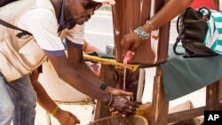 A man washes his hands at a checkpoint in Sierra Leone, as the country enters the third and final day of a three-day countrywide lockdown to combat the Ebola virus in Freetown, March. 29, 2015.