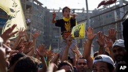 Supporters of ousted President Mohammed Morsi hold placards showing symbol that has come to represent August's violent dispersal of the Rabaah al-Adawiya mosque sit-in, Cairo, Oct. 11, 2013.