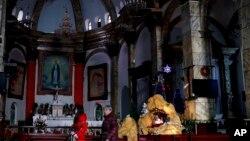 Perempuan China berjalan melewati dekorasi Natal di Gereja Katholik Nantang di Beijing. (AP Photo/Andy Wong)