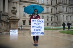 A counterprotester holds a sign supporting Michigan Gov. Gretchen Whitmer's stay-at-home order during a rally at the State Capitol in Lansing, Mich., May 14, 2020.