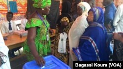 Une Tchadienne remplit les formalités avant d'aller placer son bulletin dans l'urne à côté d'autres électeurs qui attendent dans un bureau de vote à N'Djamena, Tchad, 10 avril 2016. (VOA/Bagassi Koura)