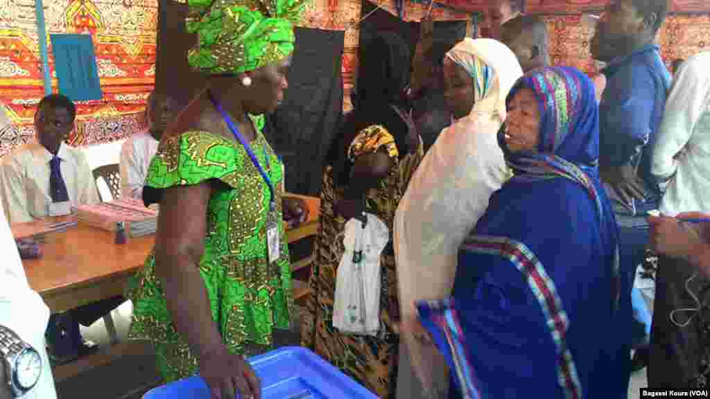 Une Tchadienne se fait aider à placer son bulletin dans l&#39;urne à côté d&#39;autres électeurs qui attendent dans un bureau de vote à N&#39;Djamena, Tchad, 10 avril 2016. (VOA/Bagassi Koura)