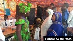 Une Tchadienne remplit les formalités avant d'aller placer son bulletin dans l'urne à côté d'autres électeurs qui attendent dans un bureau de vote à N'Djamena, Tchad, 10 avril 2016. VOA/Bagassi Koura