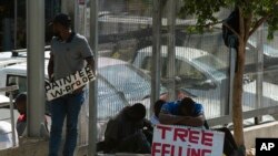 FILE: Workers advertise their skills looking for work outside a hardware store in a Johannesburg suburb, Wednesday, Feb. 26, 2020. Latest economic figures show South Africa has rebounded. 