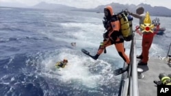 En esta captura de pantalla tomada de un video publicado por los bomberos italianos el martes 20 de agosto de 2024, se ve a buzos lanzándose al mar para seguir con la búsqueda de desaparecidos del yate, en Porticello, en el sur de Italia.