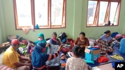 People who are displaced by floods sift through donated clothings at a temporary shelter in East Lewoleba, on Lembata Island, East Nusa Tenggara province, Indonesia, April 6, 2021.