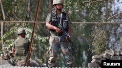 FILE - Indian army soldiers keep guard on top of a shop along a highway on the outskirts of Srinagar, Sept. 29, 2016. 