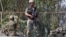 FILE - Indian army soldiers keep guard on top of a shop along a highway on the outskirts of Srinagar, Sept. 29, 2016. 