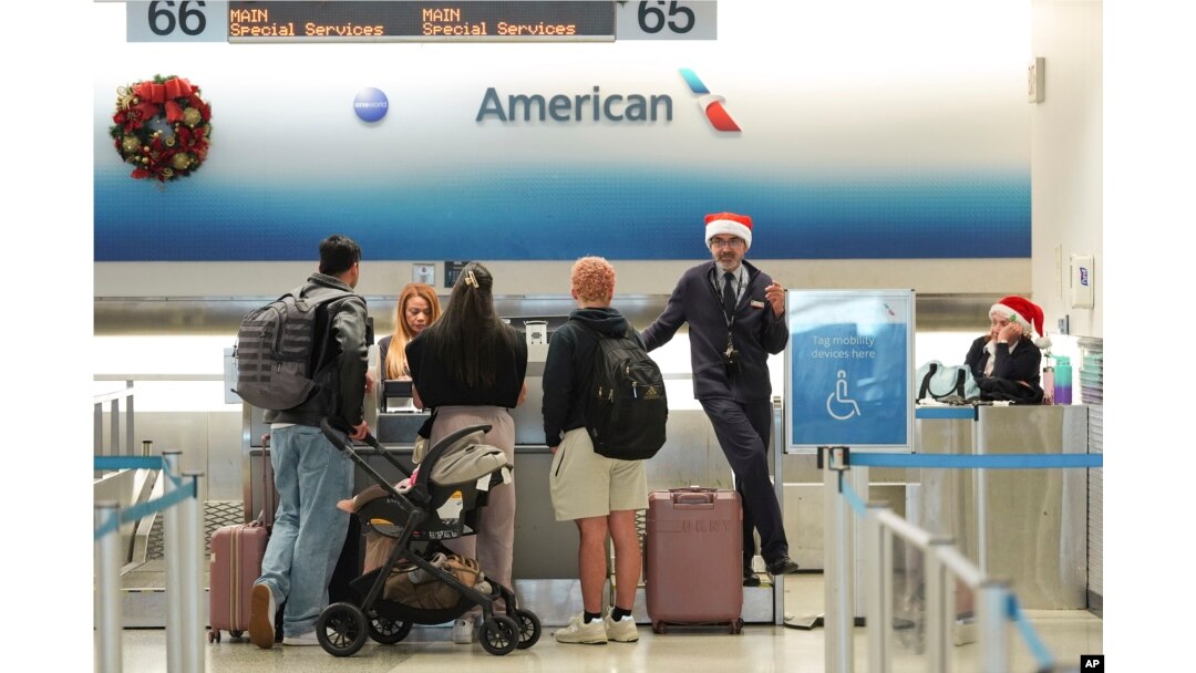 American Airlines employees, some wearing Santa Claus hats, check in travelers in the American terminal at Miami International Airport, on Christmas Eve, Dec. 24, 2024, in Miami, Florida.