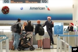 American Airlines employees, some wearing Santa Claus hats, check in travelers in the American terminal at Miami International Airport, on Christmas Eve, Dec. 24, 2024, in Miami, Florida.