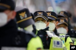 Police officers wearing face masks stand guard during a rally in downtown Seoul, South Korea, Feb. 22, 2020. South Korea on Saturday reported a six-fold jump in viral infections in four days to 433.