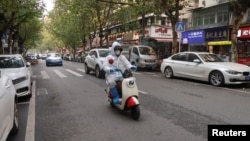 A person wearing a protective suit rides a scooter on a street, after the government eased curbs on COVID-19 control, in Wuhan, China Dec. 10, 2022.
