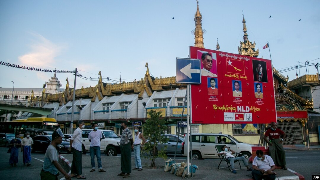 Warga beristirahat di dekat poster kampanye partai NLD di Yangoon, 15 September 2020.
