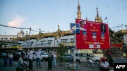 Warga beristirahat di dekat poster kampanye partai NLD di Yangoon, 15 September 2020.