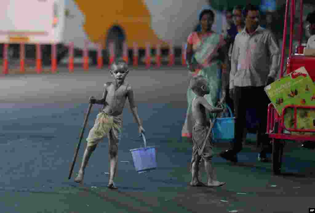 Young boys with their bodies painted and dressed as Mahatma Gandhi seek alms at a traffic intersection in Hyderabad, India.