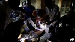 Les responsables électoraux utilisent les torches de leurs téléphones portables pour préparer les bulletins de vote à la fermeture des bureaux de vote à Kaduna, au Nigeria, samedi 28 Mars 2015