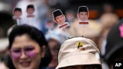 Para pendukung pasangan Prabowo Subianto-Gibran Rakabuming tampak mengenakan aksesoris dengan foto kandidat capres dan cawapres yang mereka dukung saat acara pendaftaran di Gedung KPU di Jakarta, pada 25 Oktober 2023. (Foto: AP/Achmad Ibrahim)