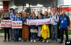FILE - Journalists of Belarusian TUT.BY media outlet hold banners reading "I don't protest but work", "This is me at work", "Freedom for journalists!", from left to right, as they stand in front of police station in Minsk, Belarus, Sept. 2, 2020.