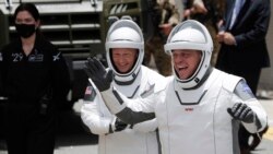 NASA astronauts Douglas Hurley, left, and Robert Behnken wave as they walk out of the Neil A. Armstrong Operations and Checkout Building on their way to Pad 39-A, at the Kennedy Space Center in Cape Canaveral, Fla., Wednesday, May 27, 2020.