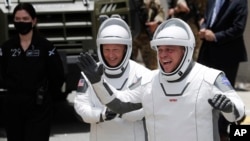 NASA astronauts Douglas Hurley, left, and Robert Behnken wave as they walk out of the Neil A. Armstrong Operations and Checkout Building at the Kennedy Space Center in Cape Canaveral, Fla., May 27, 2020.