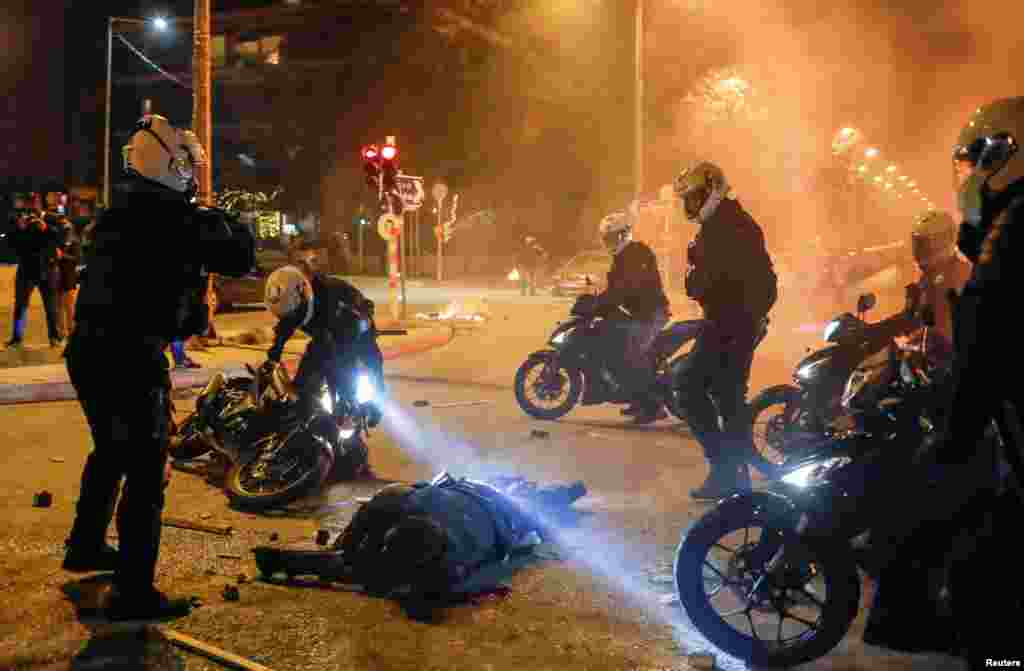 Police officers on motorcycles surround an injured companion during a demonstration against a police crackdown on gatherings, in Athens, Greece, March 9, 2021.