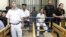 Police guard Egyptian activist Ahmed Douma (C), who is seen behind bars, during his trial at the New Cairo court, on the outskirts of Cairo, Egypt, June 3, 2013.