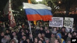 People wave the Russian flag and hold posters reading "This election is farce!" and "Give the country choice back" during an opposition rally in Moscow, Russia, December 5, 2011.