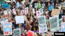 FILE - Students hold banners as they attend a climate school strike in London, Britain, Feb. 14, 2020.