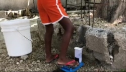 When a person steps on the pedal, the bucket releases water. (Photo: Matiado Vilme / VOA)