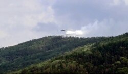 FILE - In this July 10, 2020 file image taken from video provided by Russian Emergency Ministry, a Russian aircraft releases water in the Trans-Baikal National Park in Buryatia, southern Siberia.