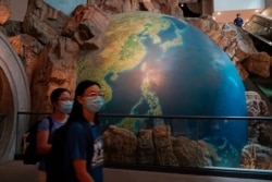 Visitors wearing masks to help protect against the coronavirus walk past an earth sculpture, at the Hong Kong Museum of History, in Hong Kong, Oct. 16, 2020.