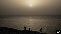 Orang-orang menyaksikan matahari terbenam sementara awan debu Sahara menyelimuti Kota Havana, Kuba, 24 Juni 2020. (Foto: AP)