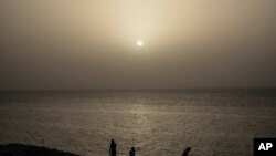 People watch the sunset while a cloud of Sahara dust hangs in the air in Havana, Cuba, on June 24, 2020. 