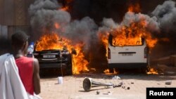 Wani mutumi yana kallon motoci su na ci da wuta a wani otel din da 'yan majalisar dokoki ke zaune ciki a Ouagadougou