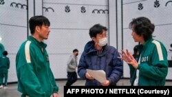 (FILES) Sutradara Hwang Dong-hyuk (tengah) memberikan arahan kepada aktor Lee Jung-jae (kanan) dalam salah satu adegan "Squid Game" (Handout / Netflix / AFP) 