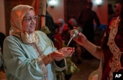 FILE — A woman sprinkle orange blossom water after it was distilled, in a cultural center in Marrakech, Morocco, March 23, 2024.