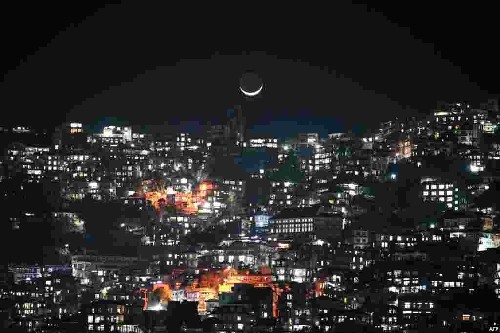 A crescent moon is seen over homes on a hillside in Aizawl, the capital of the northeastern Indian state of Mizoram.