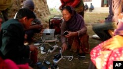 Young villagers charge their mobile phones from a generator in the destroyed village of Paslang near the epicenter of Saturday’s massive earthquake in the Gorkha District of Nepal, April 28, 2015. 