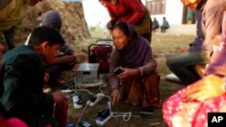 Warga Nepal korban gempa di desa Paslang mengisi baterei ponsel mereka dari sebuah generator (foto: dok). Pasca gempa, Nepal masih mengalami kelangkaan makanan.