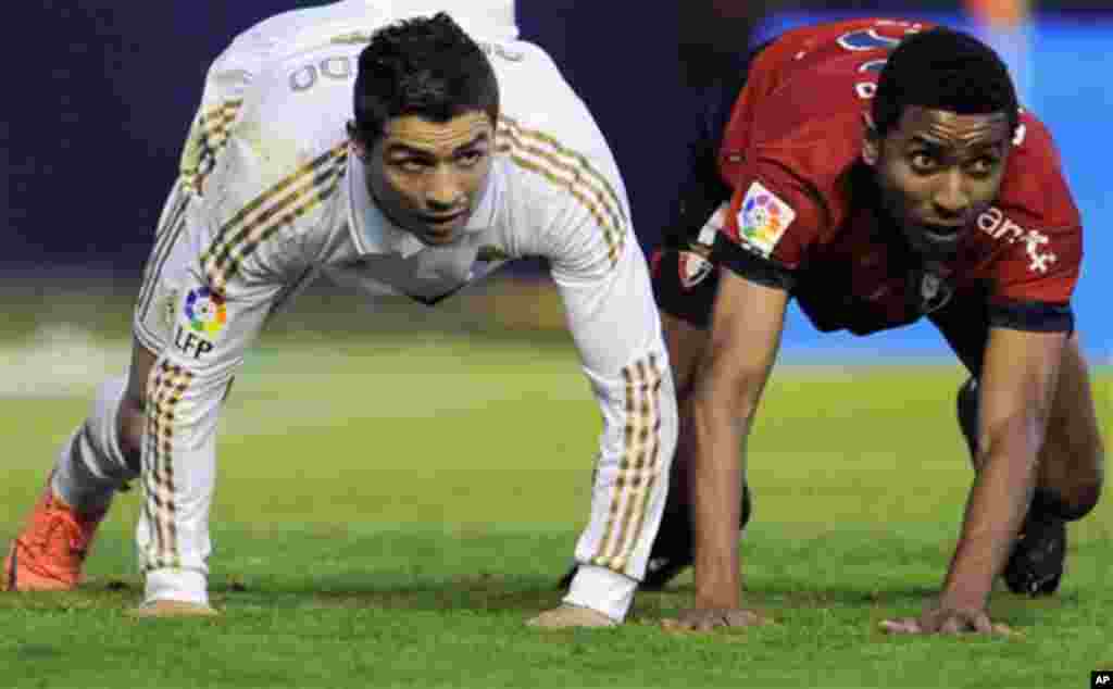 Real Madrid's Cristiano Ronaldo from Portugal, left, falls on the pitch with Osasuna's Roversio Rodrigues from Brazil during their Spanish La Liga soccer match, at Reyno de Navarra stadium in Pamplona, northern Spain, Saturday March 31, 2012. Real Madri