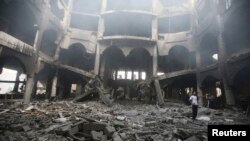 A Palestinian looks at the remains of a commercial center, which witnesses said was hit by an Israeli airstrike on Saturday, in Rafah in the southern Gaza Strip, Aug. 24, 2014. 