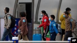 Returnees from the Hubei Province leave from the West Train Station to board buses in Beijing on March 26, 2020.