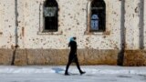 (FILE) A woman walks outside St. Iveron Convent, which was heavily damaged by artillery and gun fire during battles for the local airport in the course of Russia-Ukraine conflict, in Donetsk, Ukraine, February 25, 2025.