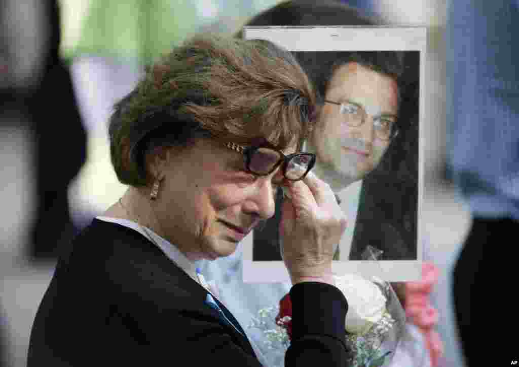 A woman wipes away tears as she holds up a picture during a ceremony at ground zero in New York, Sept. 11, 2017.